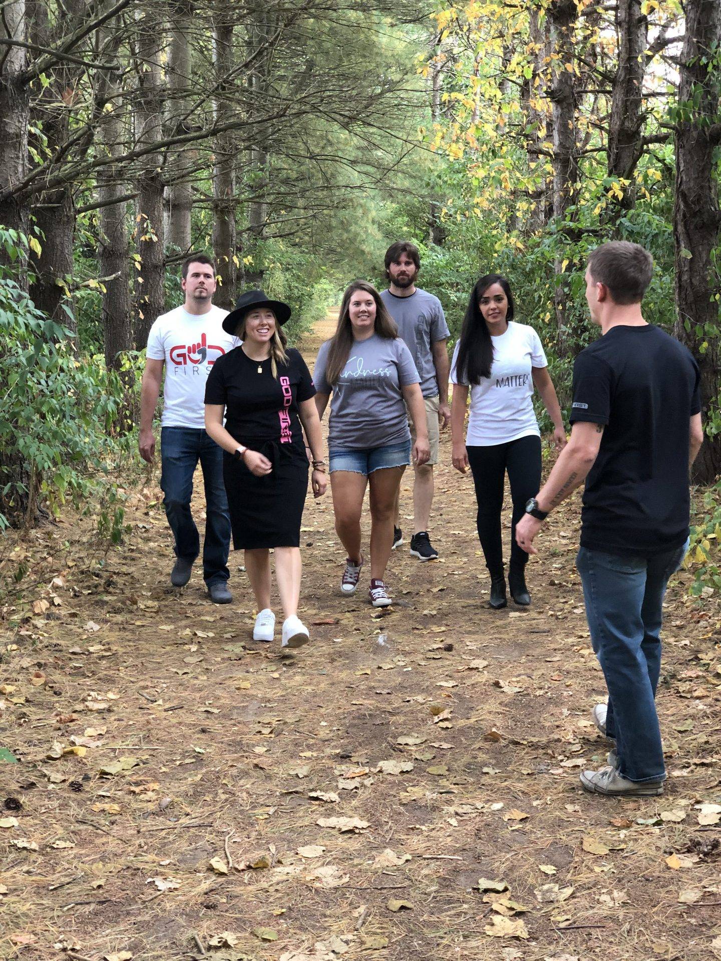 Group of people walking in a forest with three women and three men.